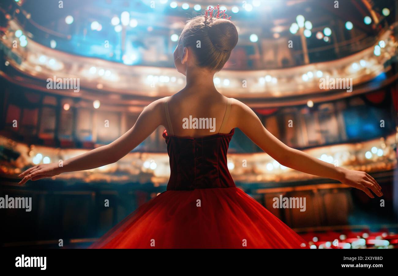 Una bambina carina che sogna di diventare una ballerina. Bambina in un tutu rosso che danza sul palco. Foto Stock