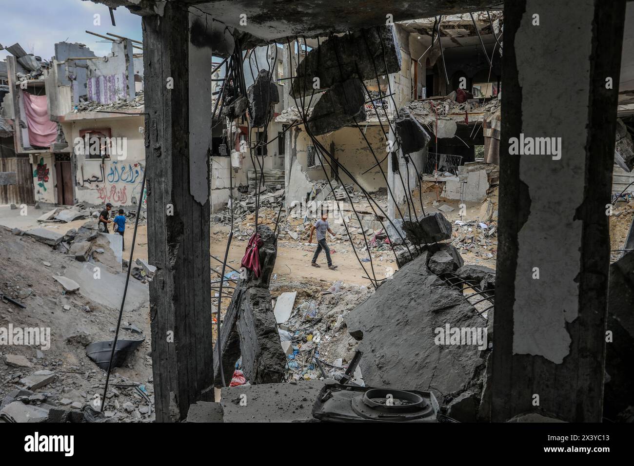 Rafah, territori palestinesi. 29 aprile 2024. I palestinesi passano davanti alla massiccia distruzione della casa appartenente alla famiglia al-Khatib dopo i bombardamenti degli aerei da guerra israeliani. Crediti: Abed Rahim Khatib/dpa/Alamy Live News Foto Stock