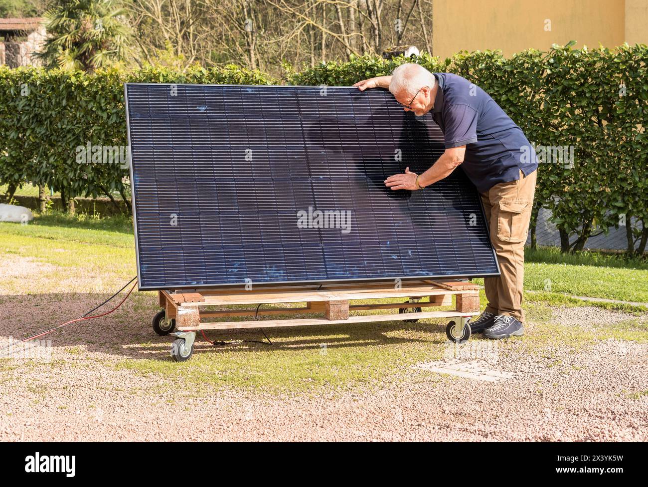 Uomo anziano con pannello solare fotovoltaico in giardino. Foto Stock