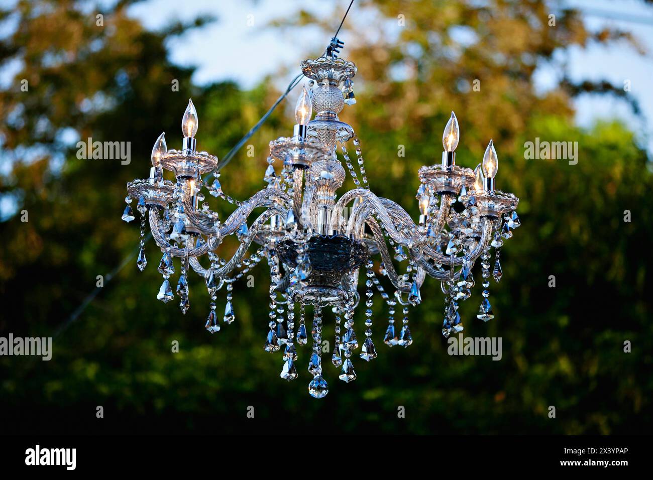 Elegante lampadario appeso all'esterno, cristalli scintillanti al crepuscolo. Foto Stock