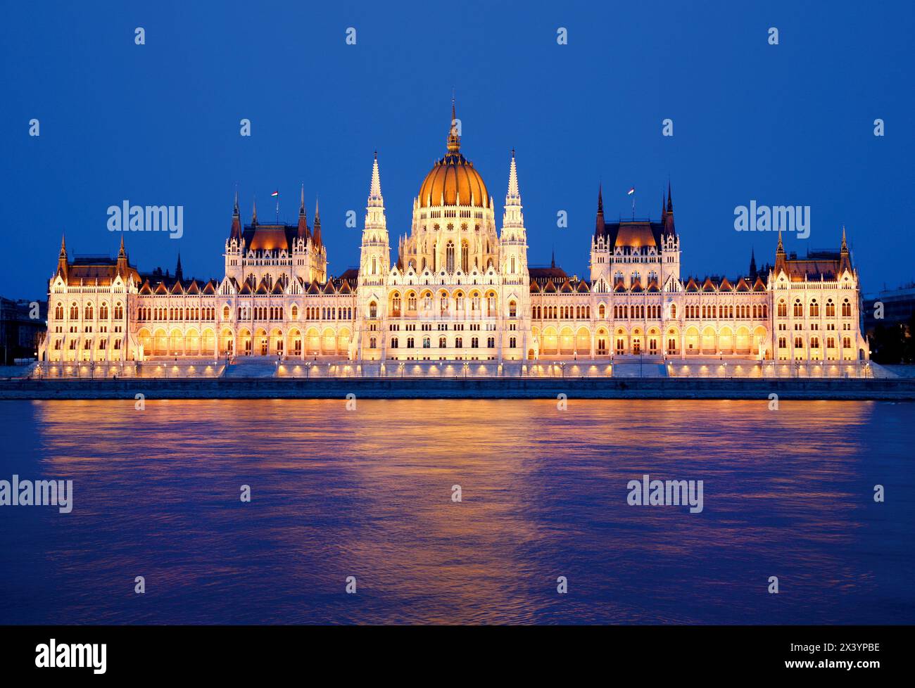 Parlamento a Budapest di notte, edificio storico illuminato che si riflette sull'acqua del fiume Foto Stock