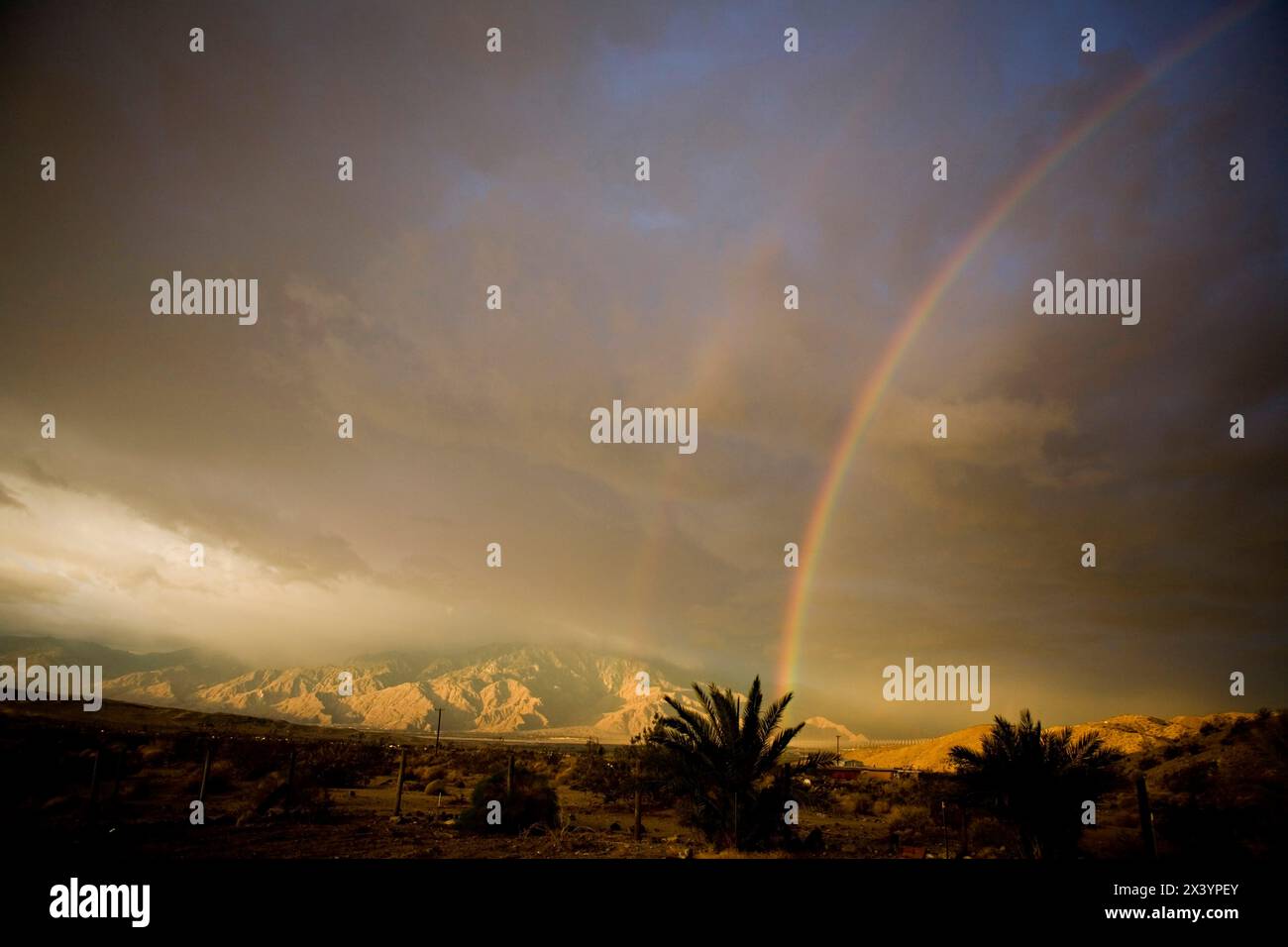 Archi arcobaleno sulle montagne desertiche baciate dalla tempesta, uno spettacolo naturale. Foto Stock
