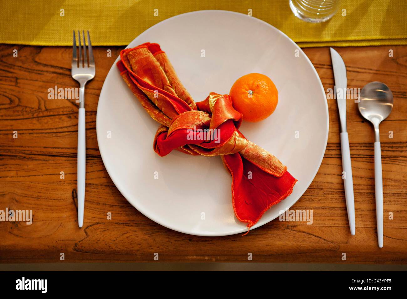 Tavolo rustico con tovagliolo arancione vivace e mandarino fresco Foto Stock