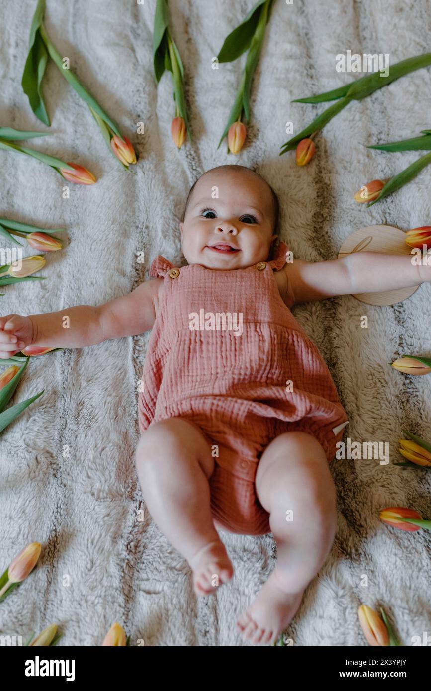 una bambina orribile di rosa, che brilla tra i tulipani primaverili Foto Stock