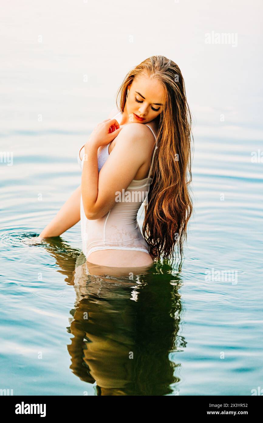 Bella donna caucasica in lingerie bianca in piedi nel fiume Foto Stock