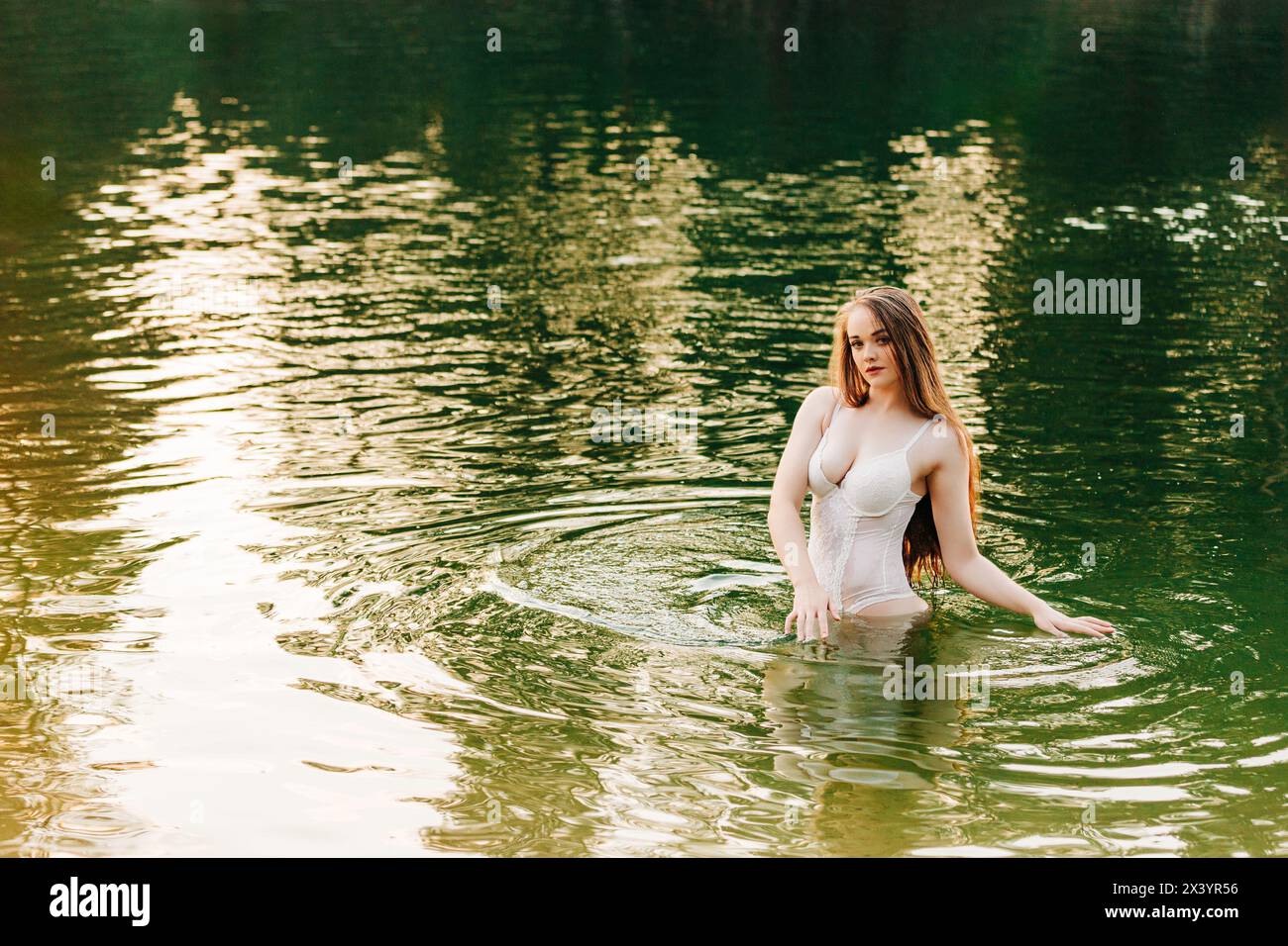 Splendida donna millenaria in lingerie bianca in piedi sul fiume Foto Stock