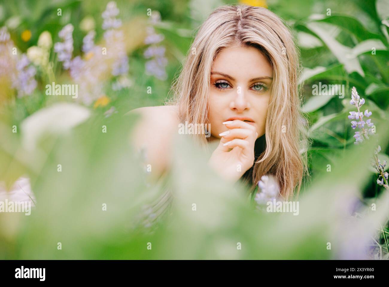 Faccia da vicino di una ragazza adolescente sdraiata nella foresta in mezzo a fiori selvatici Foto Stock
