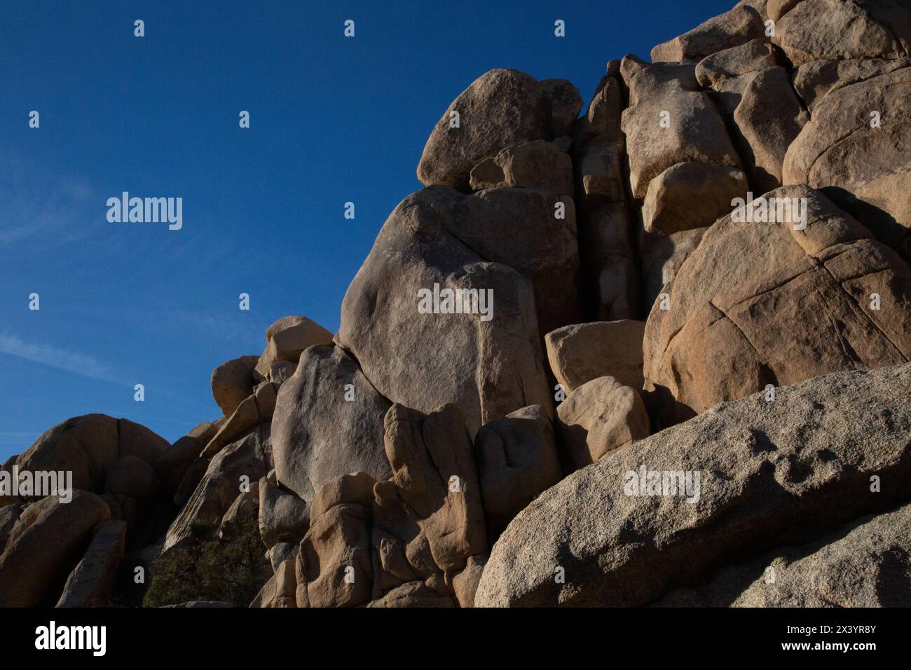 Giganti di granito illuminati dal sole si ergono alti sotto il cielo di Joshua Tree Foto Stock