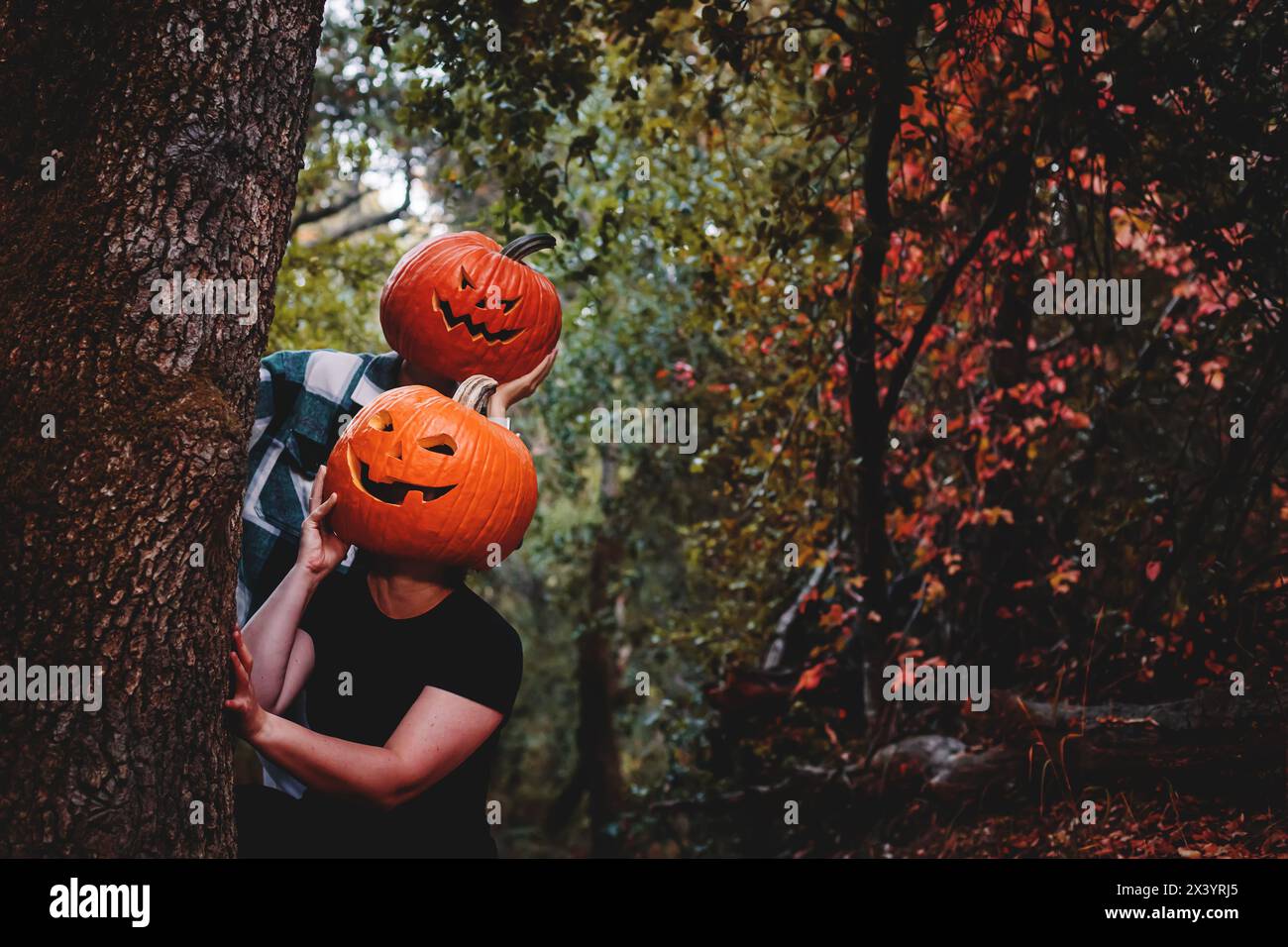 Due amici che indossano teste di zucca scolpite di Halloween con volti spaventosi Foto Stock