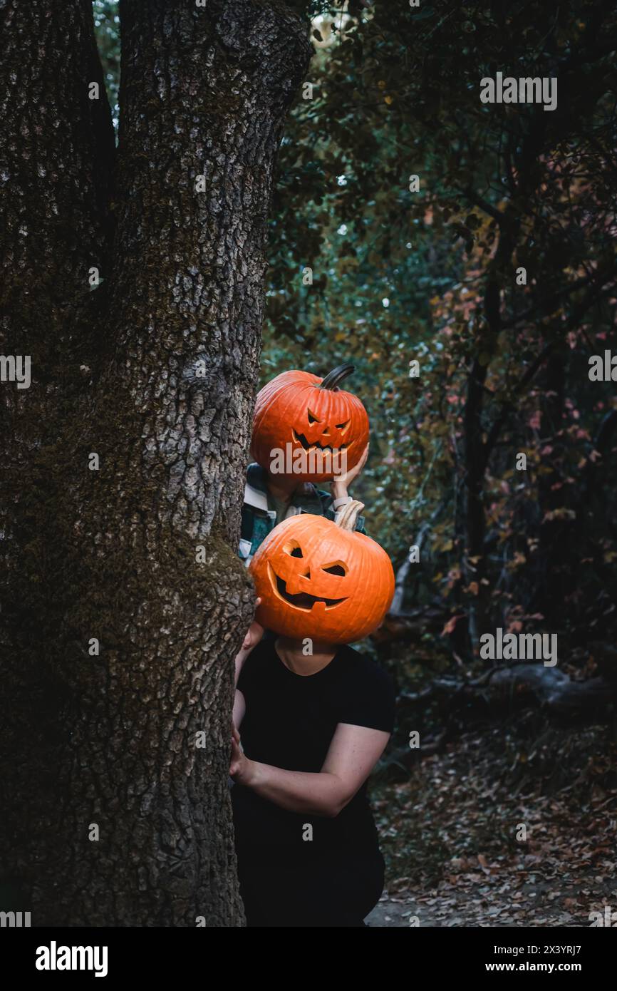 Due amici che indossano teste di zucca scolpite di Halloween con volti spaventosi Foto Stock