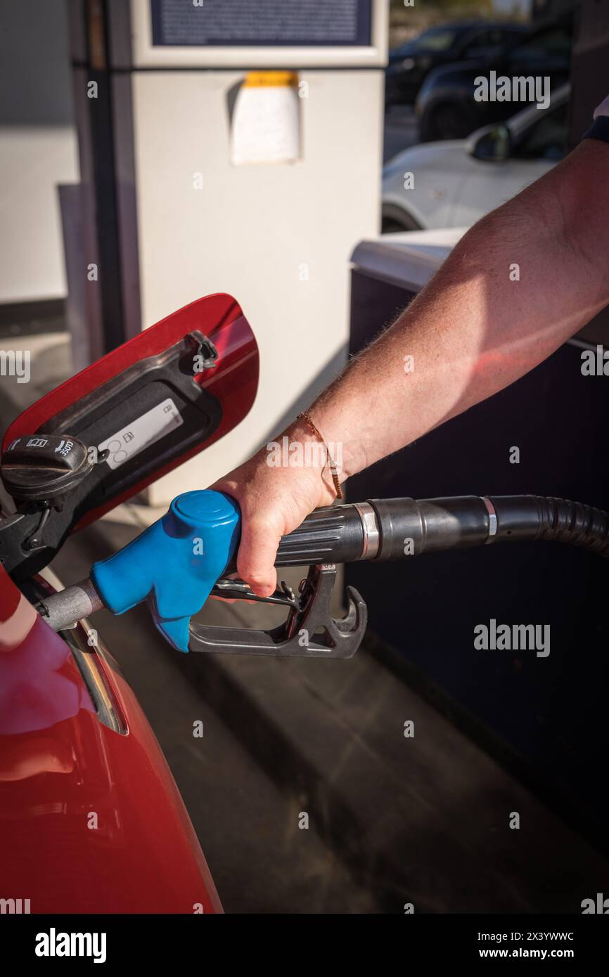 uomo mano il rifornimento di benzina e il riempimento del serbatoio presso la stazione di servizio o la stazione di servizio pompa alla vettura rossa Foto Stock