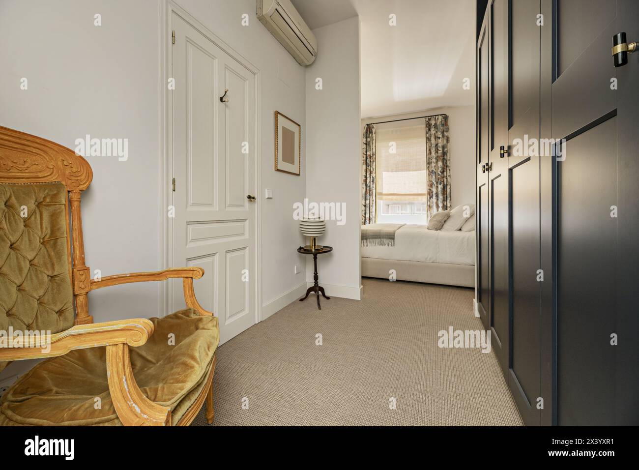 Corridoio con spogliatoio, accesso al letto con tavoli in legno e grande finestra con tende a motivi geometrici Foto Stock