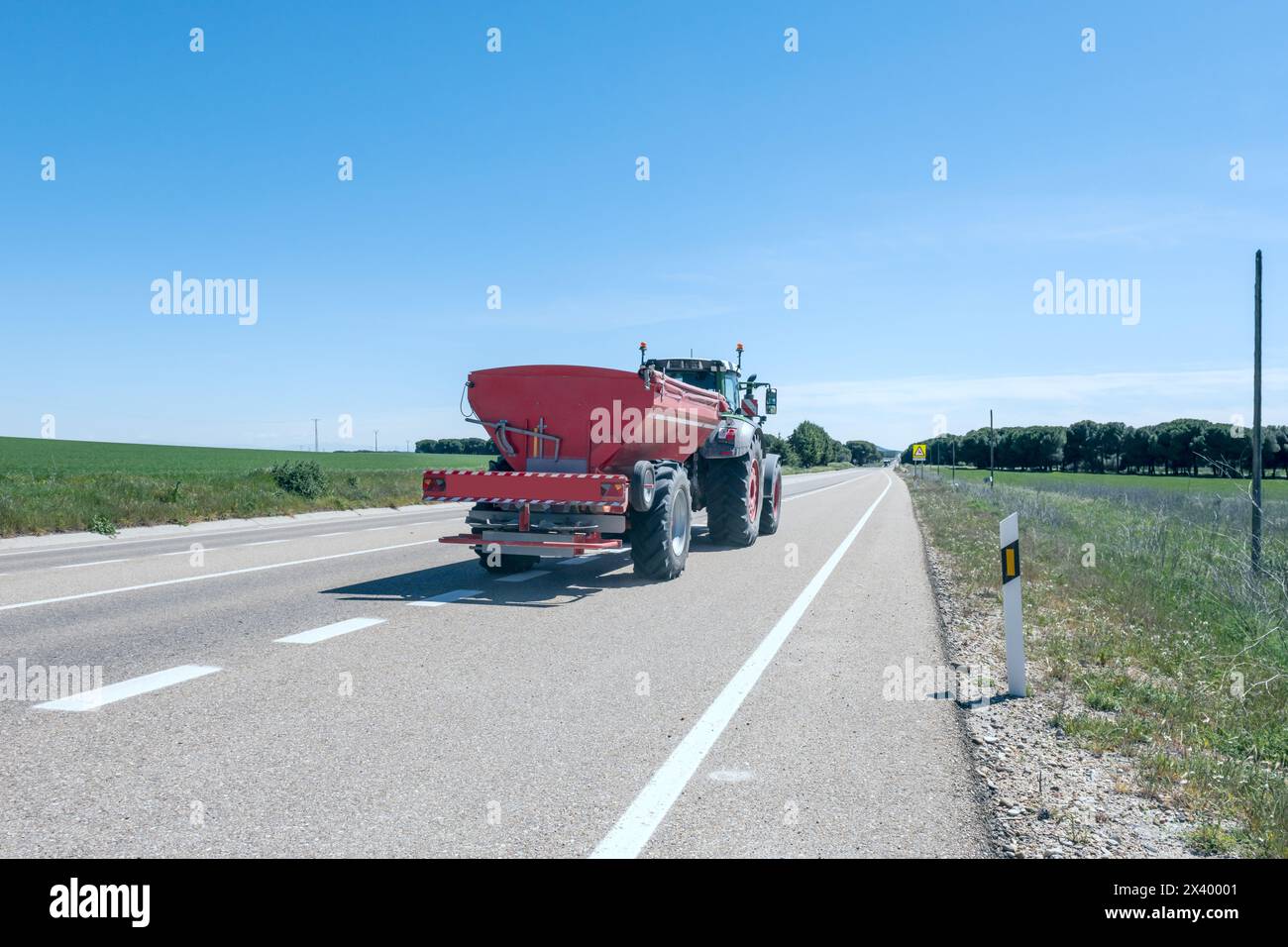 Contrassegni degli indicatori verniciati su una strada provinciale su cui viaggia un trattore-rimorchio Foto Stock