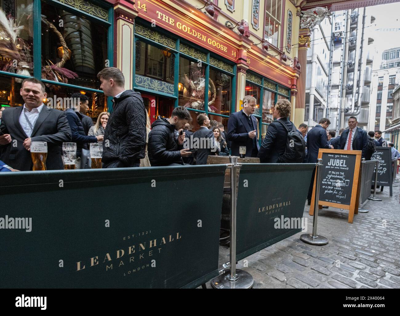 Gli uomini d'affari e i lavoratori della città bevono un drink all'ora di pranzo al Golden Goose di Leadenhall Market, City of London, Inghilterra, Regno Unito Foto Stock