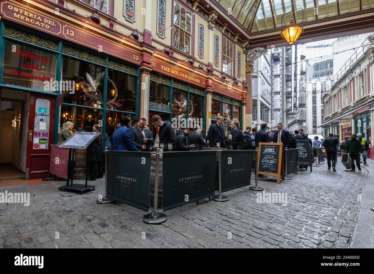Gli uomini d'affari e i lavoratori della città bevono un drink all'ora di pranzo al Golden Goose di Leadenhall Market, City of London, Inghilterra, Regno Unito Foto Stock