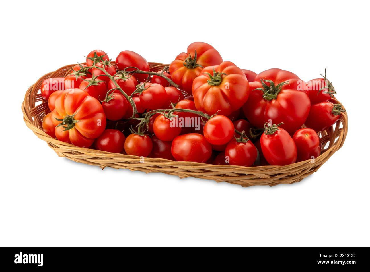 Pomodori rossi di vari tipi e forme in cestello di vimini isolato su bianco con percorso di ritaglio incluso. Pomodori e pomodori ciliegini Foto Stock