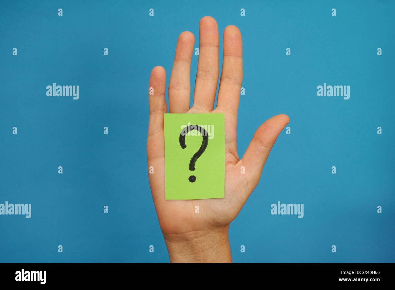 Nota di carta verde con il simbolo del punto interrogativo nel palmo di una donna. Sfondo blu. Foto Stock