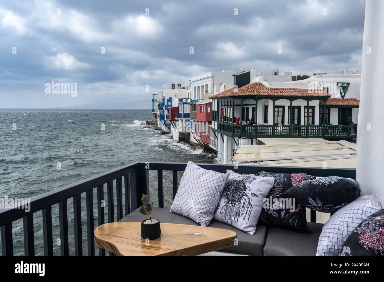 Accogliente balcone fronte mare con vista sul cielo grigio tempestoso e sugli edifici bianchi lungo la riva del Mar Egeo sull'isola del Mar Egeo meridionale... Foto Stock