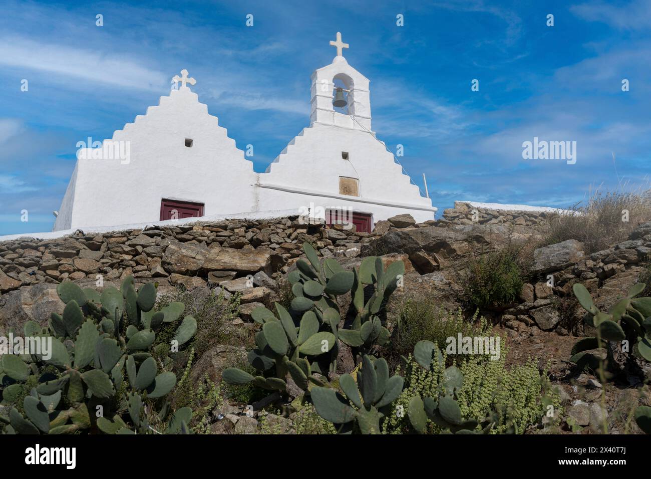 Chiesa bianca con campana e croce su un campanile contro un cielo blu, sull'isola di Mykonos, Grecia; Mykonos, Egeo meridionale, Grecia Foto Stock