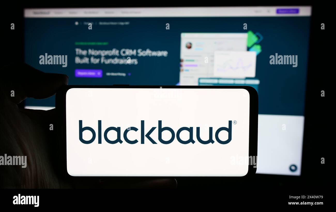 Persona che detiene un cellulare con il logo della società di software statunitense Blackbaud Inc. Di fronte alla pagina Web aziendale. Mettere a fuoco il display del telefono. Foto Stock