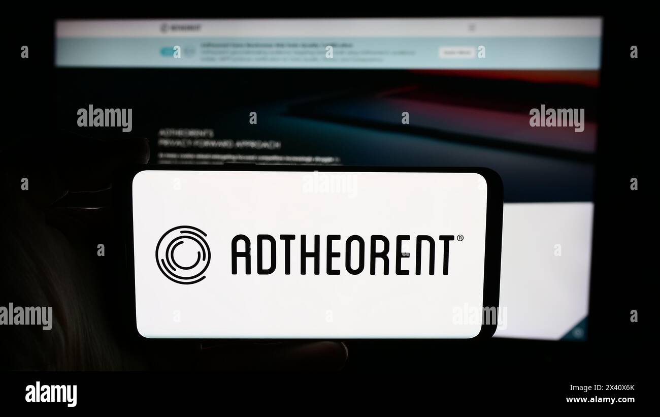 Persona che detiene un cellulare con il logo della società di software pubblicitario statunitense AdTheorent Inc. Di fronte alla pagina Web aziendale. Mettere a fuoco il display del telefono. Foto Stock