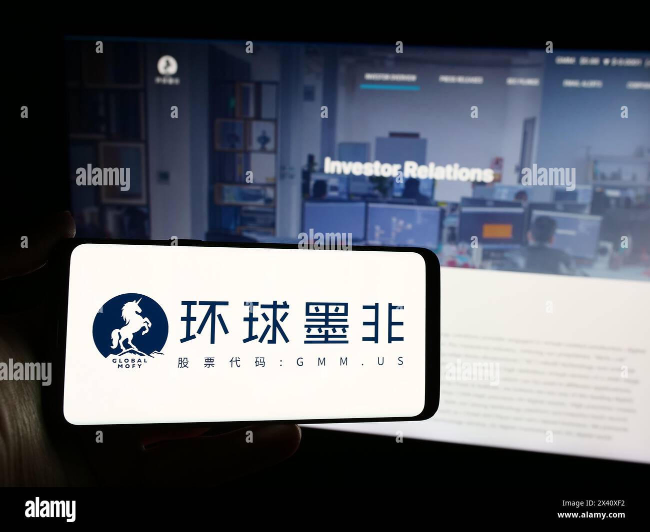 Persona che detiene uno smartphone con il logo della società cinese Global Mofy Metaverse Limited davanti al sito Web. Mettere a fuoco il display del telefono. Foto Stock