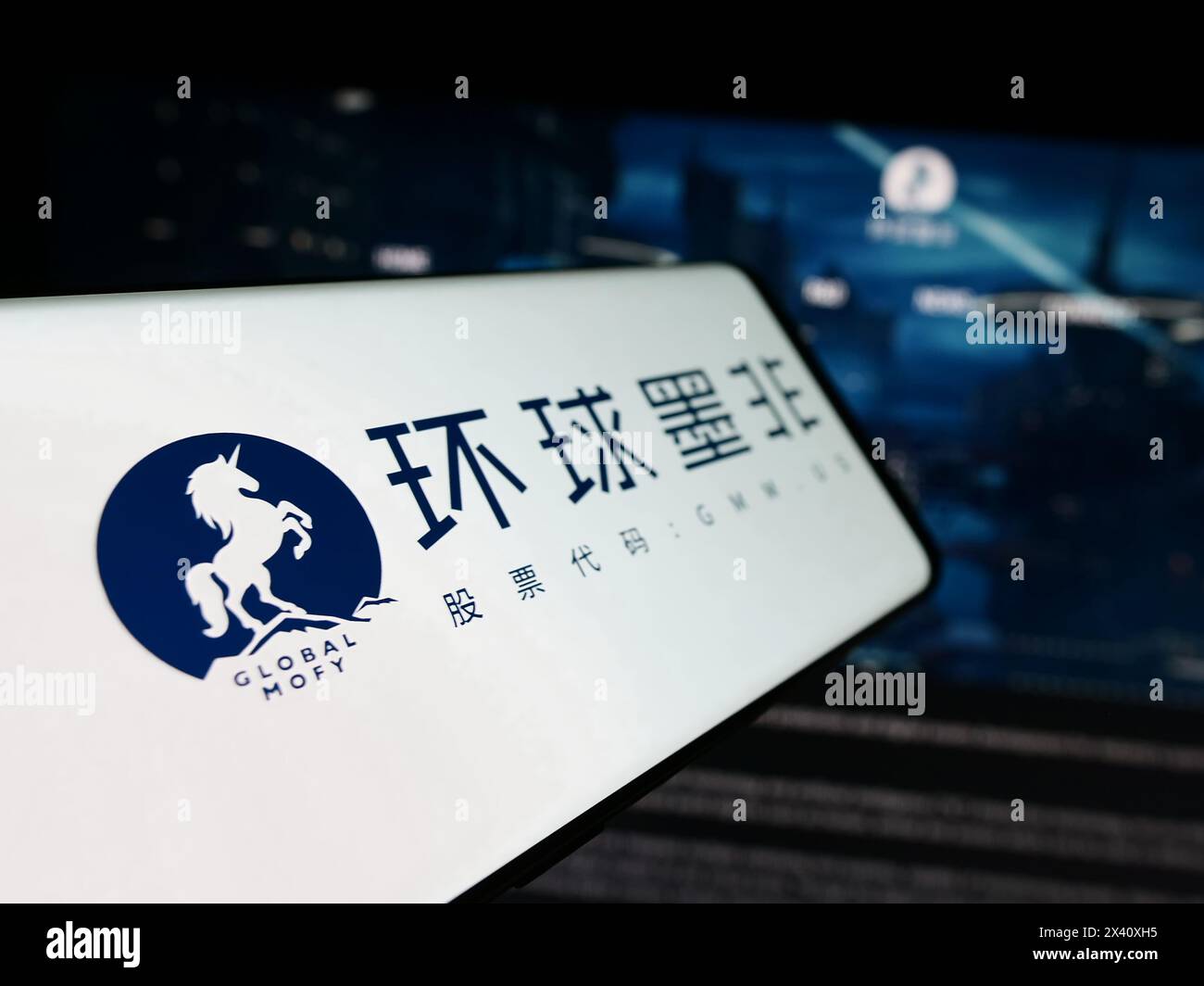 Telefono cellulare con logo della società cinese Global Mofy Metaverse Limited davanti al sito Web aziendale. Mettere a fuoco la parte sinistra del display del telefono. Foto Stock