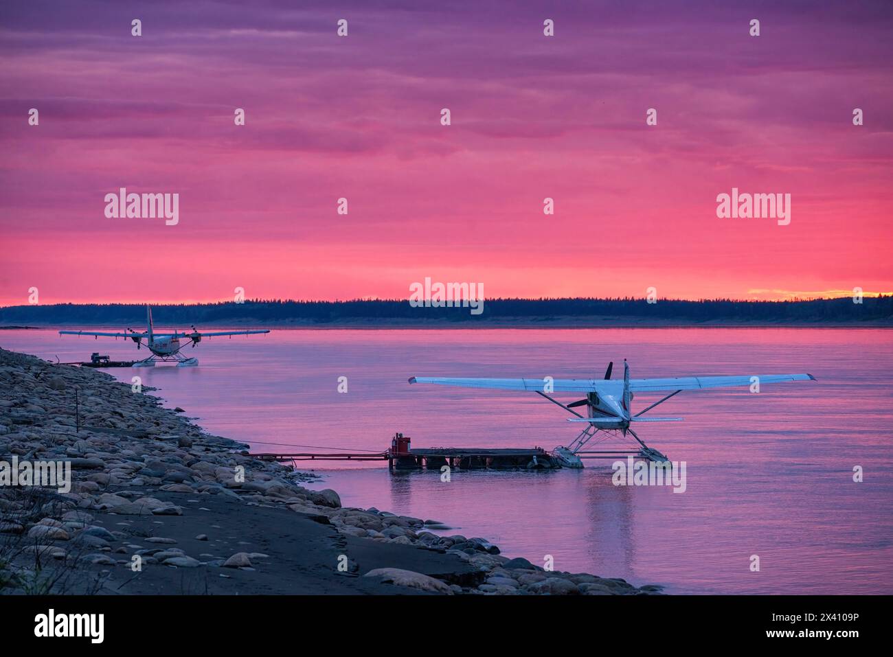 Idrovolanti nel fiume Mackenzie mentre il sole tramonta illumina le nuvole in splendidi rosa; Fort Simpson, territori del Nord-Ovest, Canada Foto Stock
