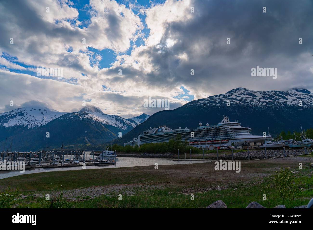 Le navi da crociera sono attraccate al porto di Skagway, nell'Alaska meridionale. Grandi montagne adornano il paesaggio e creano una scena magnifica per... Foto Stock