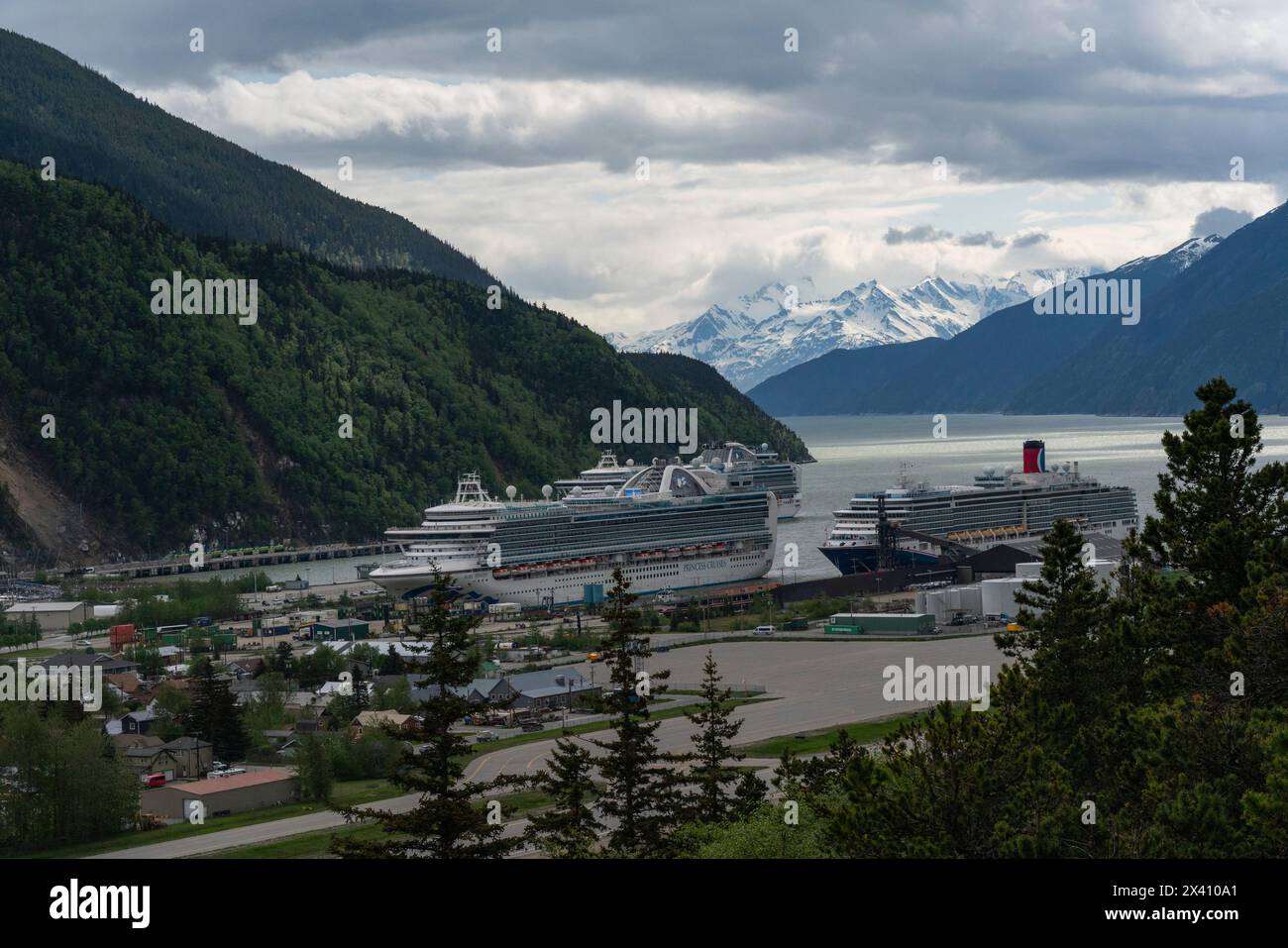 Le navi da crociera sono attraccate al porto di Skagway, nell'Alaska meridionale. Grandi montagne adornano il paesaggio e creano una scena magnifica per... Foto Stock