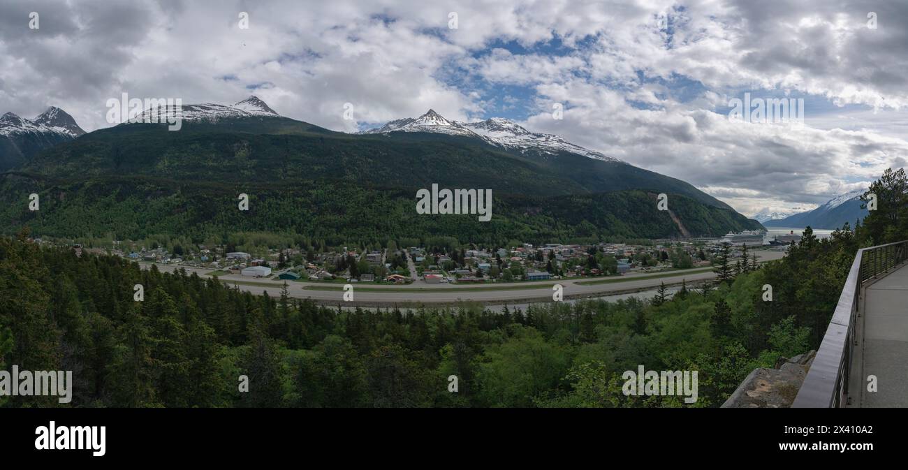 Le navi da crociera sono attraccate al porto di Skagway, nell'Alaska meridionale. Grandi montagne adornano il paesaggio e creano una scena magnifica per... Foto Stock