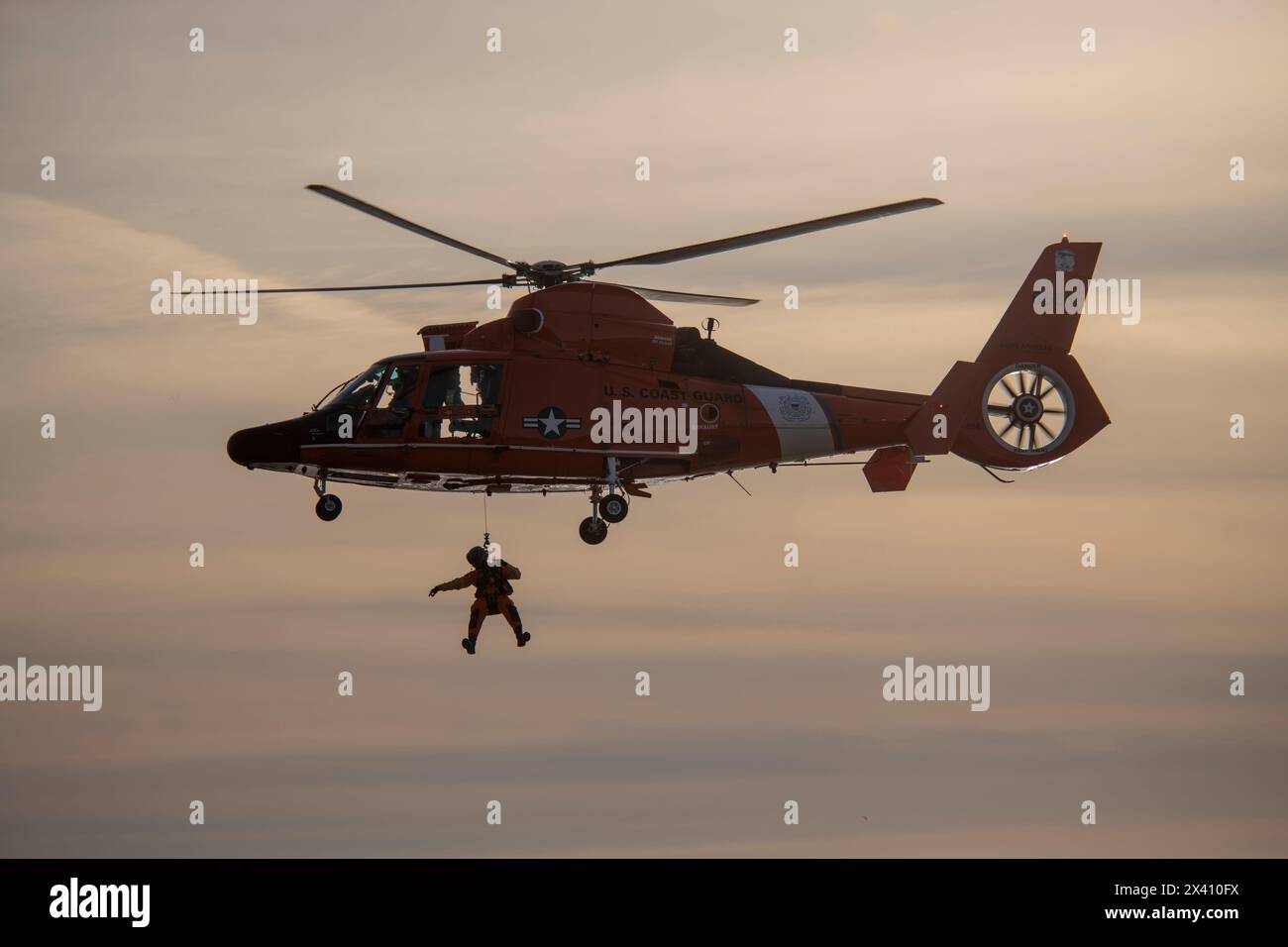 Equipaggio della Guardia Costiera degli Stati Uniti sospeso sotto un Eurocopter MH-65 che esegue esercitazioni di soccorso presso il Cape Disappointment State Park vicino alla foce del ... Foto Stock