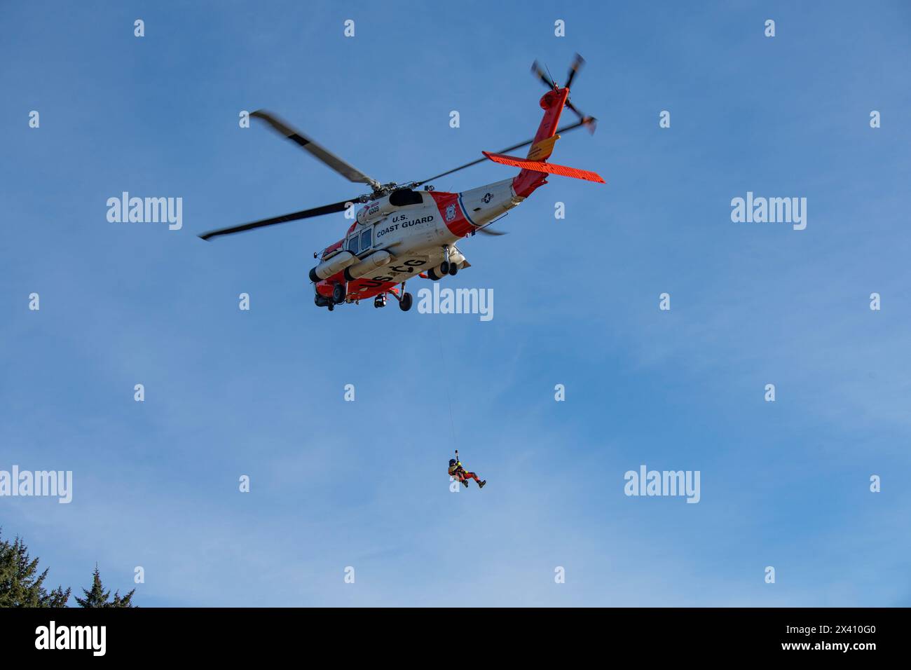 Equipaggio della Guardia Costiera degli Stati Uniti sospeso sotto un Sikorsky MH-60J Jayhawk che svolge esercitazioni di soccorso al Cape Disappointment State Park vicino al... Foto Stock