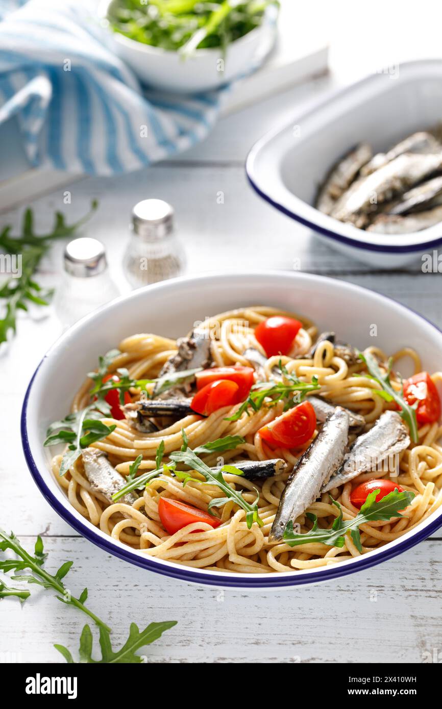 Pasta integrale con sardine, pomodoro e rucola. Cucina italiana e siciliana. Foto Stock