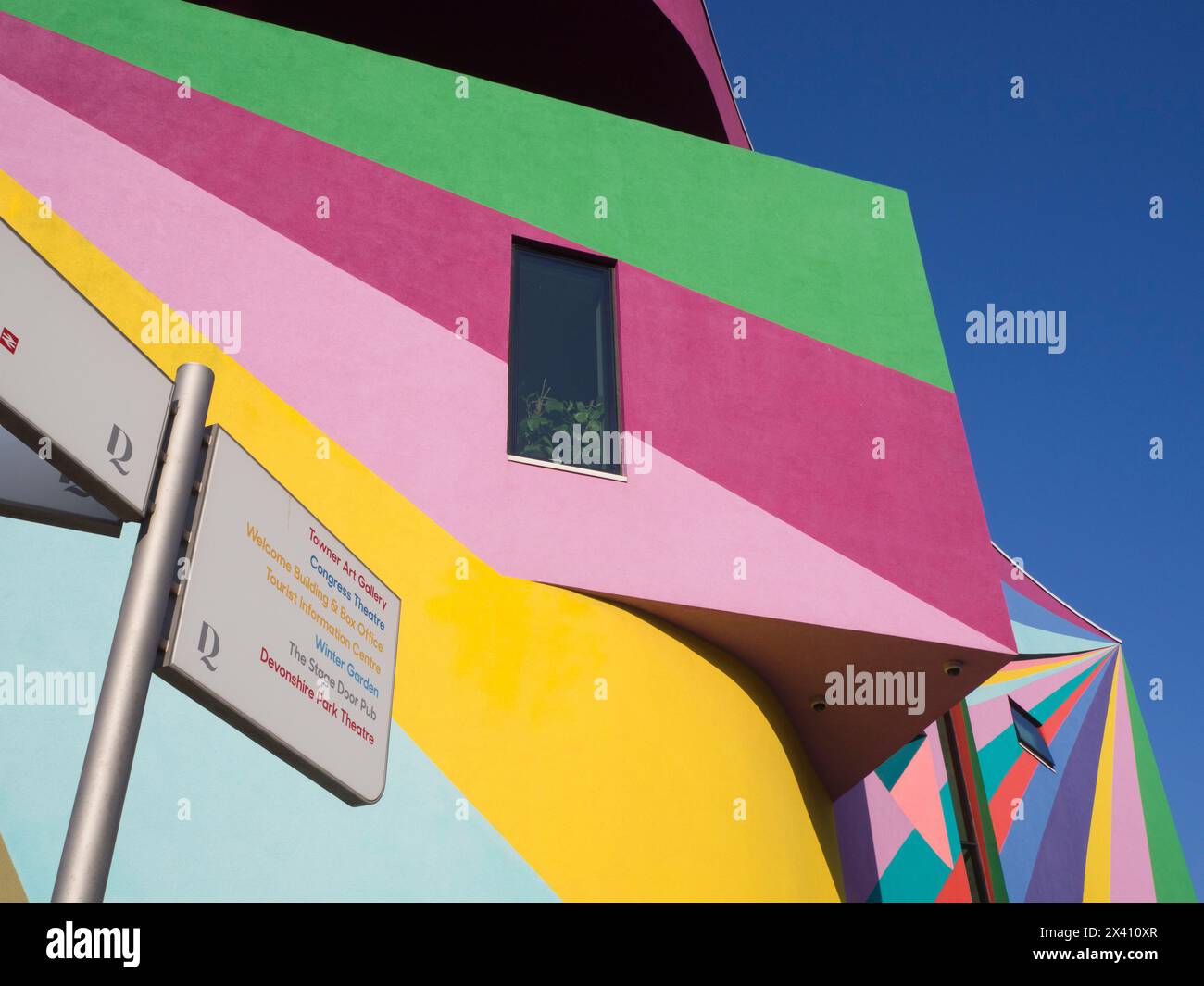 Pareti esterne su una galleria d'arte dipinte in colori vivaci contro un cielo blu e un cartello con una lista di punti di riferimento locali Foto Stock