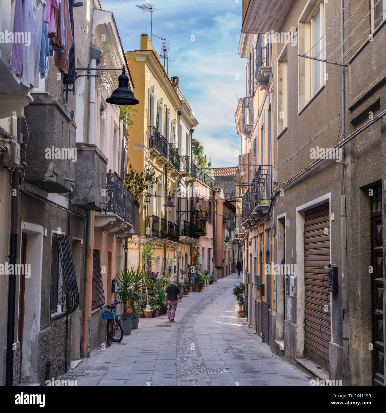 L'uomo cammina lungo una stretta strada residenziale in Italia; Cagliari, Cagliari, Italia Foto Stock