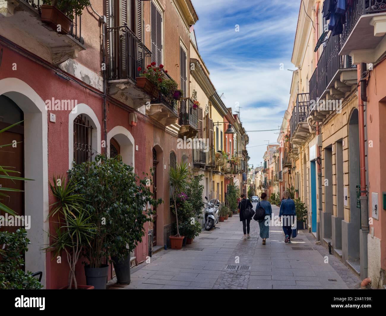 Tre donne d'affari camminano lungo una stretta strada residenziale in Italia; Cagliari, Cagliari, Italia Foto Stock