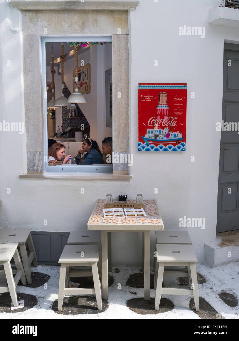 Cena sull'isola di Mykonos, con i clienti che mangiano all'interno e seduti su un patio all'aperto; Mykonos, Grecia Foto Stock