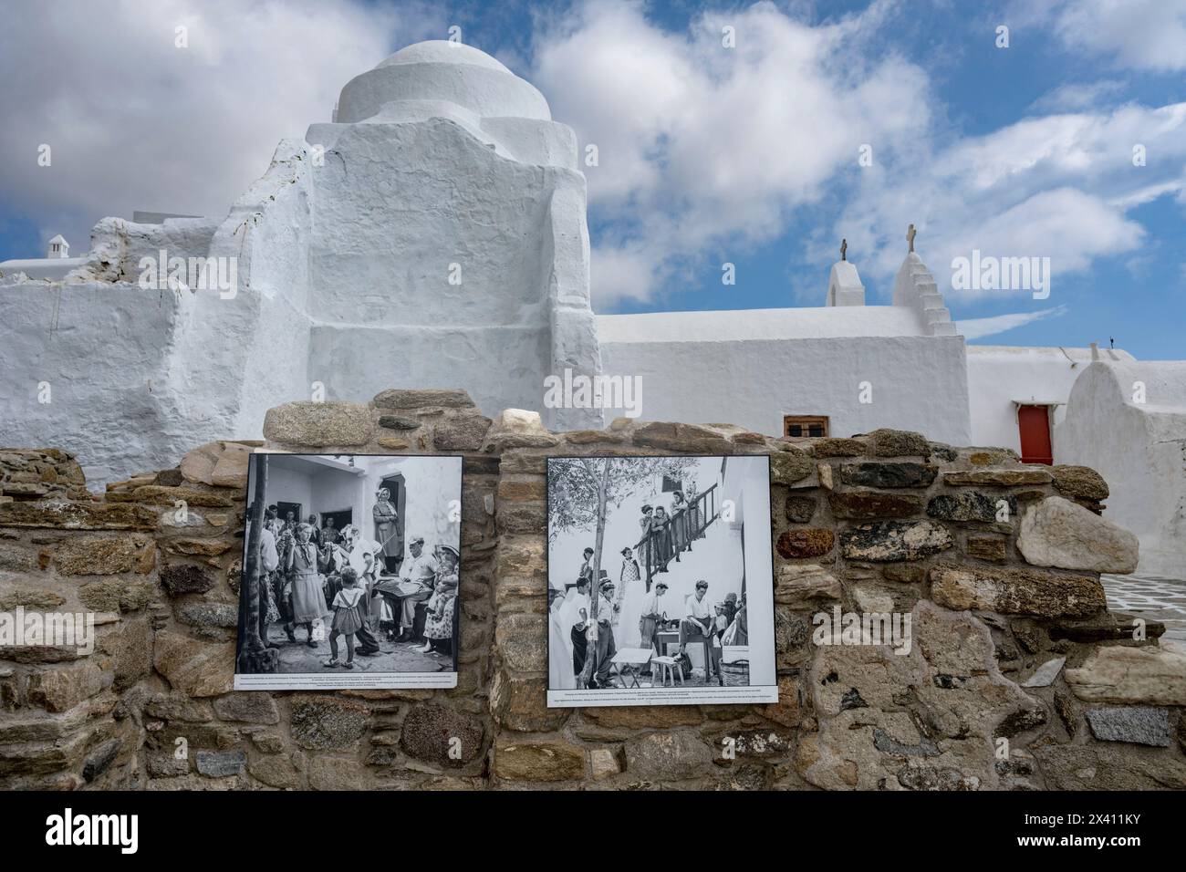 Fotografie storiche in bianco e nero montate su un muro di pietra a Mykonos, con una chiesa bianca sullo sfondo; Mykonos, Egeo meridionale, Grecia Foto Stock