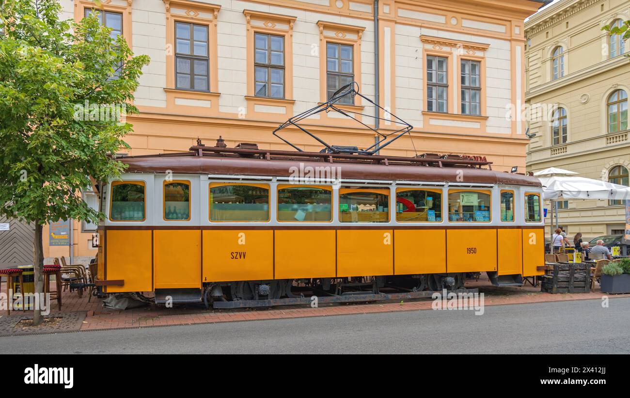 Szeged, Ungheria - 30 luglio 2022: Tram giallo d'epoca convertito al Blues Cafe e settima fermata a Somogy Street nella zona pedonale. Foto Stock