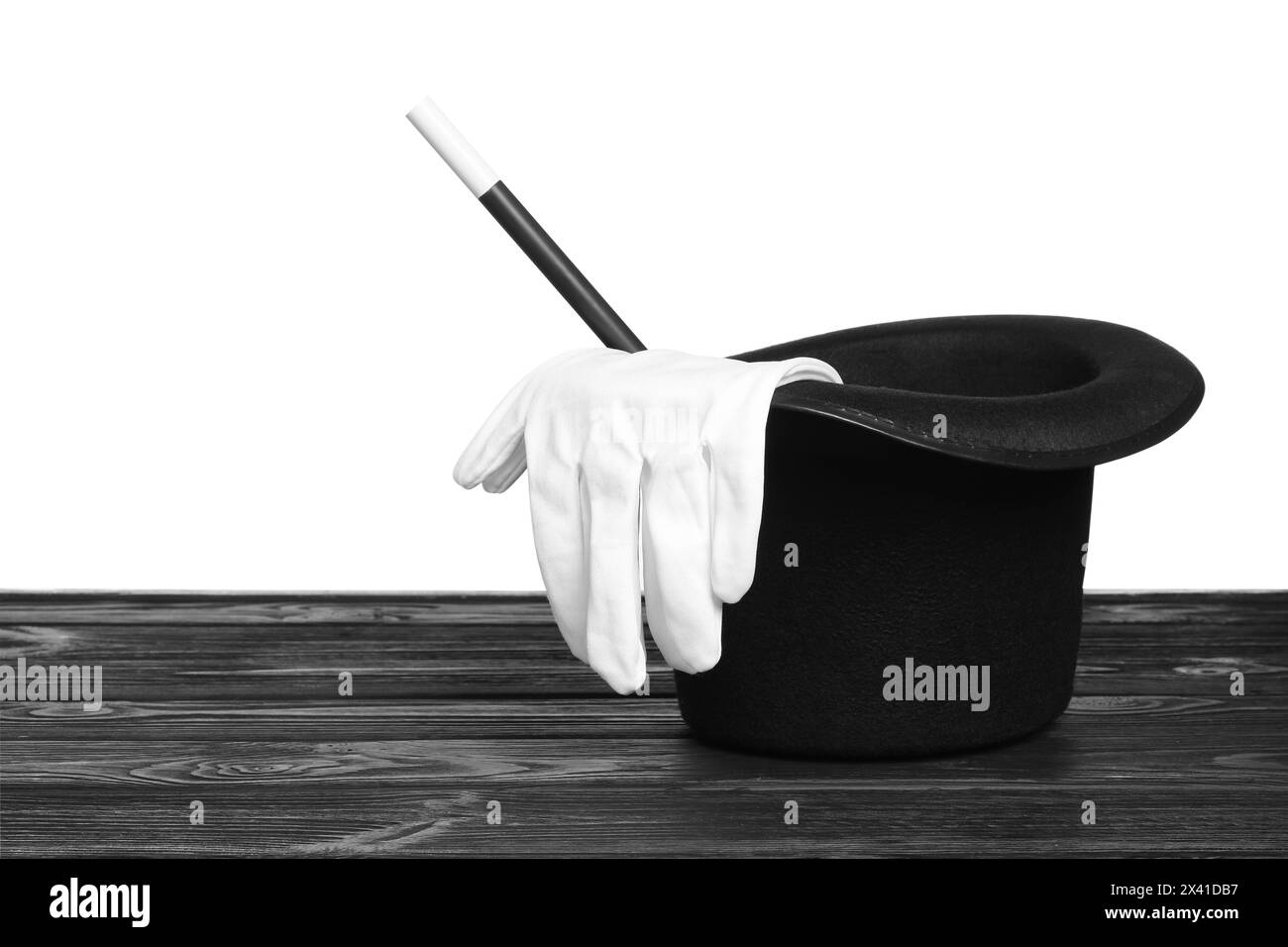 Cappello, guanti e bacchetta da mago su un tavolo di legno su sfondo bianco Foto Stock