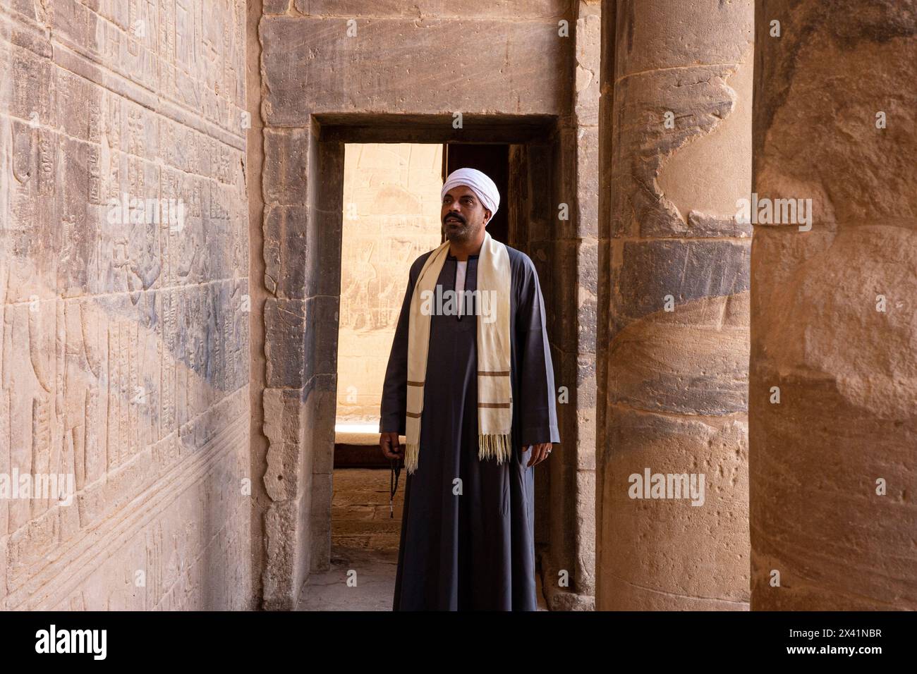 Un uomo egiziano in abito tradizionale all'interno del Tempio di Iside presso il complesso del Tempio di file (un sito patrimonio dell'umanità dell'UNESCO) sull'isola di Agilkia, in Egitto Foto Stock