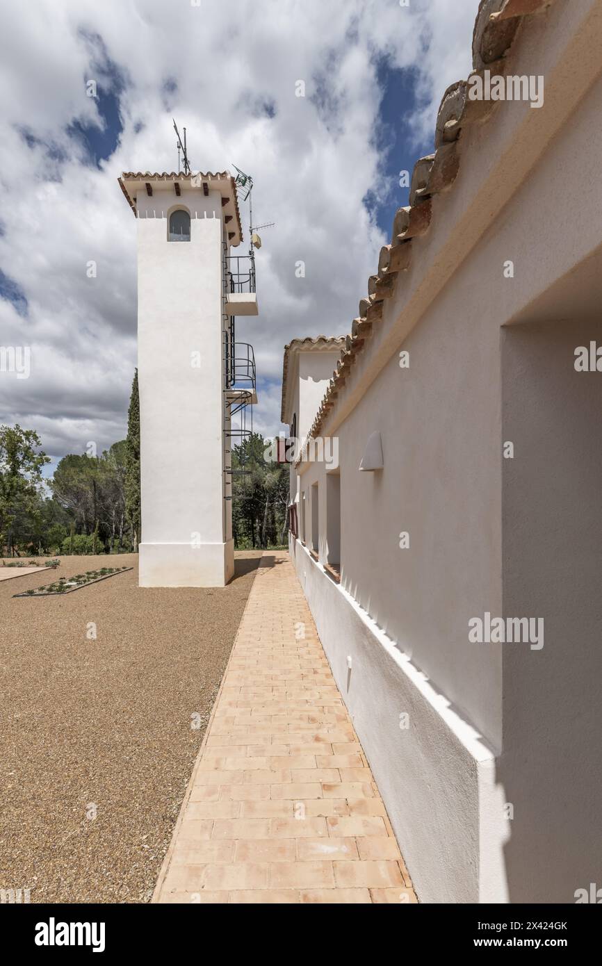 Un lungo corridoio in una casa di campagna con facciate bianche e pavimenti in terracotta in una giornata con cieli luminosi con nuvole che passano Foto Stock