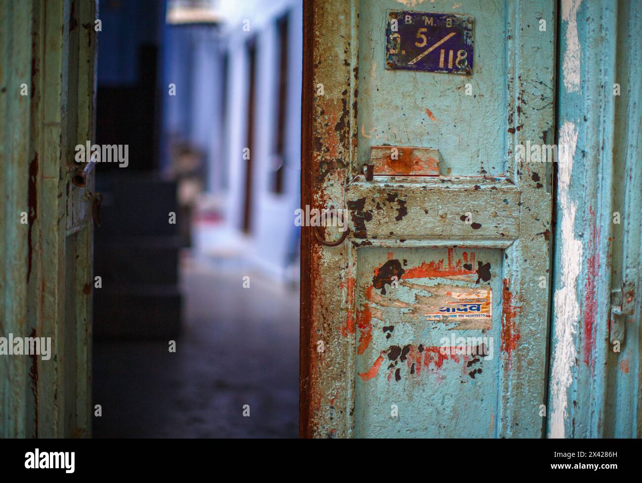 Porta per metà aperta e fortemente segnata per una dimora a Varanasi, India. Foto Stock