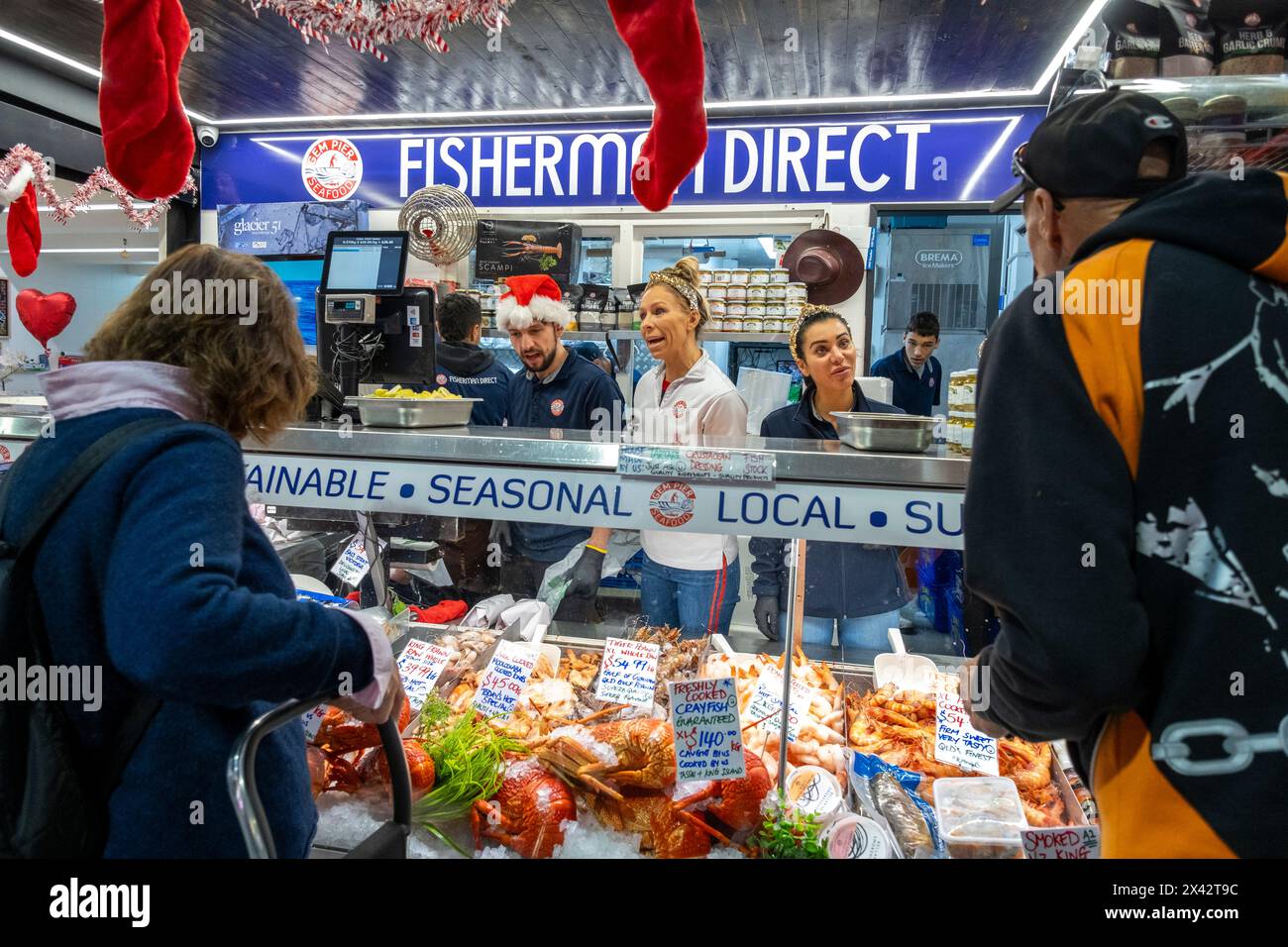 I negozianti servono i clienti al Fisherman Direct stall del South Melbourne Market. South Melbourne, Victoria, Australia. Foto Stock