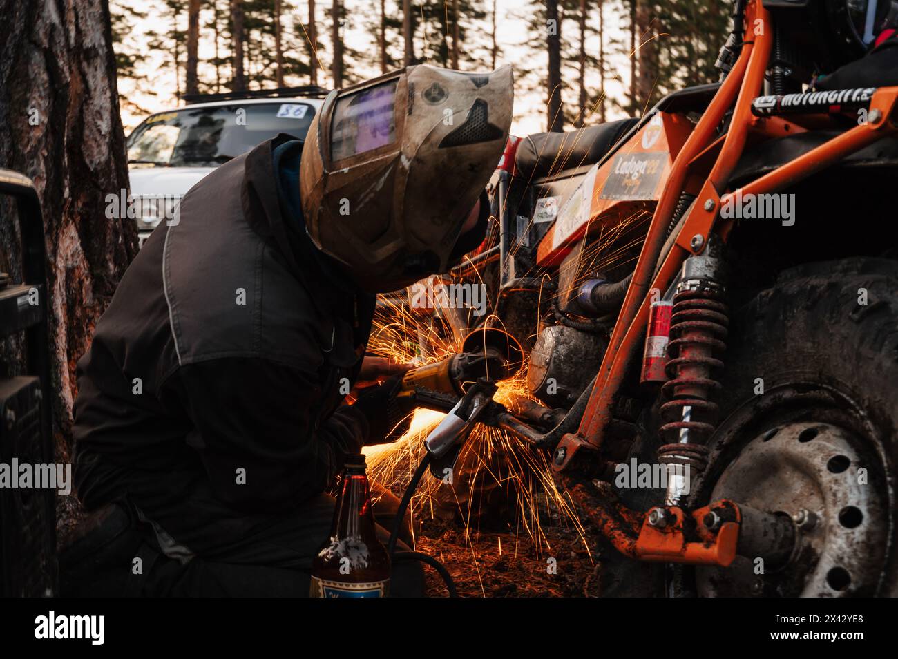 REPUBBLICA DI CARELIA, RUSSIA - CIRCA GIUGNO 2022: Torneo fuoristrada Ladoga Trophy 2022 intorno al lago Ladoga. Il meccanico ripara una motocicletta con una smerigliatrice dopo la gara Foto Stock