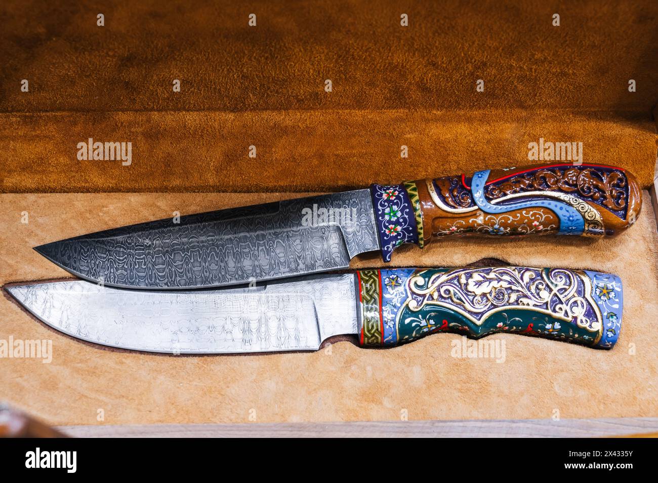 Due coltelli tradizionali uzbeki orientali realizzati in acciaio Damasco in una scatola regalo in legno in Uzbekistan a Tashkent Foto Stock