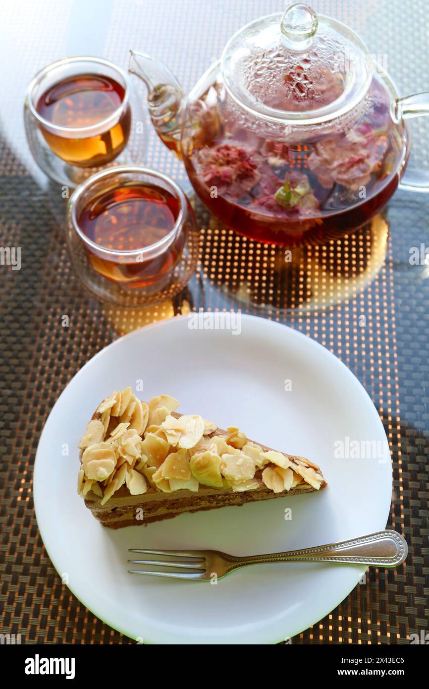 Primo piano della gustosa torta di mandorle al caffè servita con fragranza di tè alla rosa Foto Stock