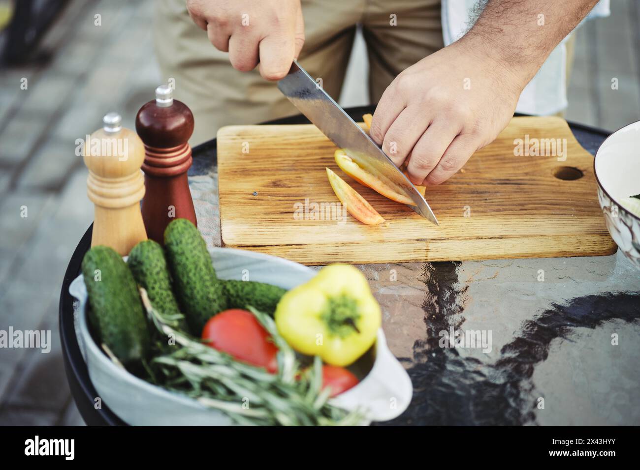 Uomo irriconoscibile che affetta peperone dolce per insalata di verdure Foto Stock