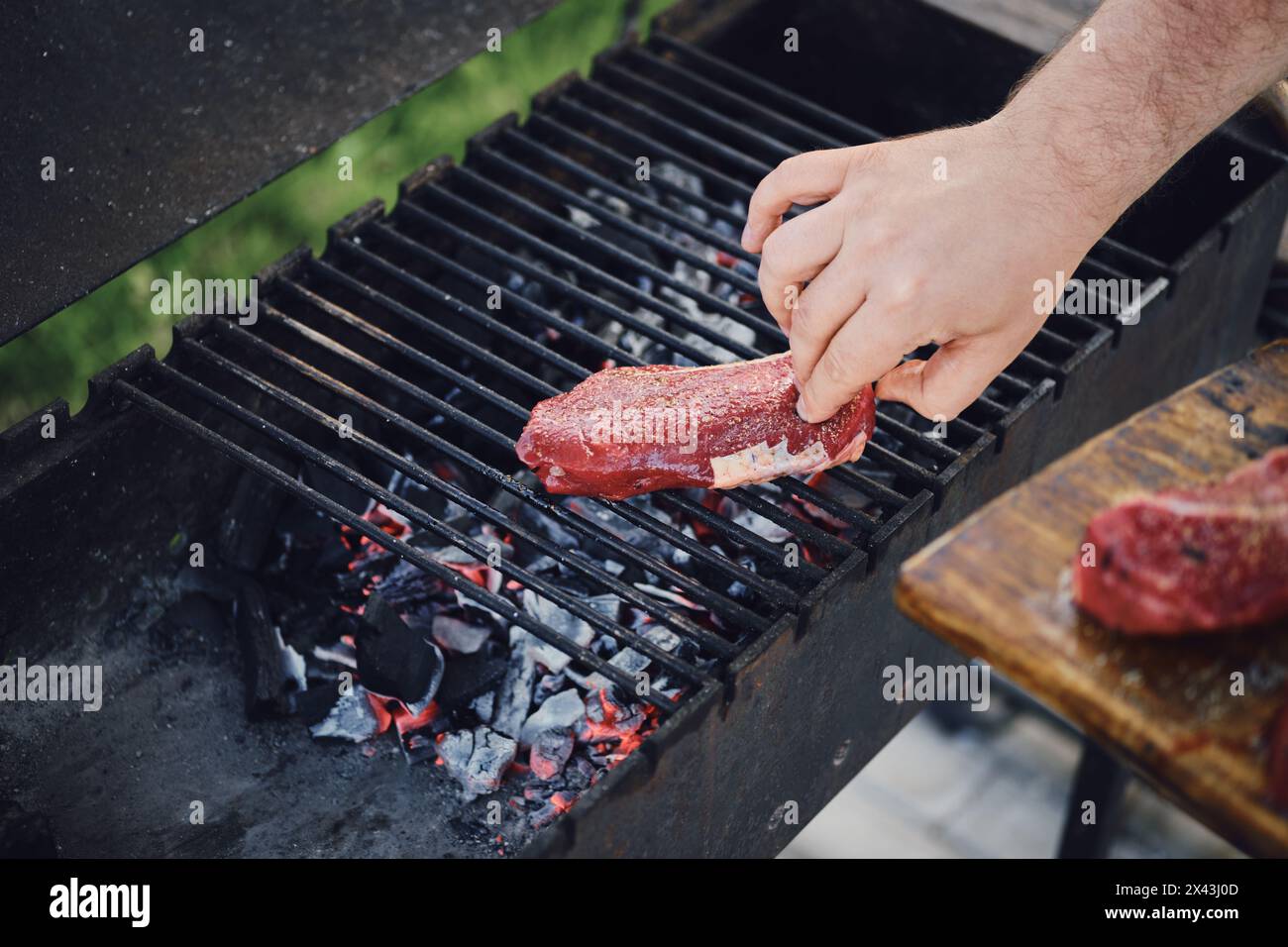 L'uomo irriconoscibile ha messo la bistecca cruda sulla griglia Foto Stock